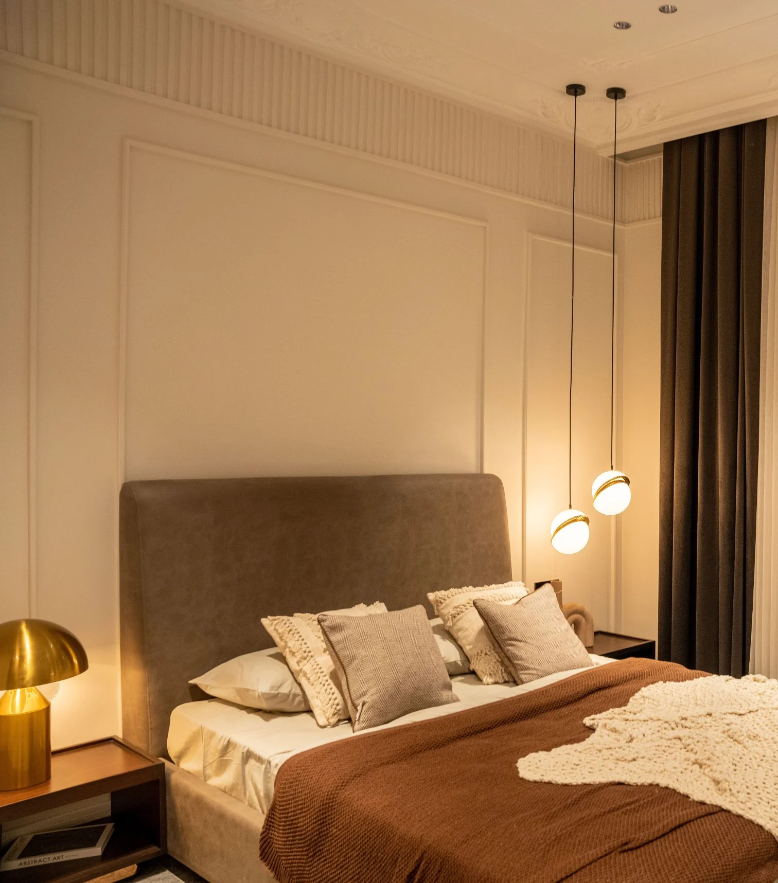 Made bed with a warm bedside lamp and pendant lights in a prepared guest bedroom
